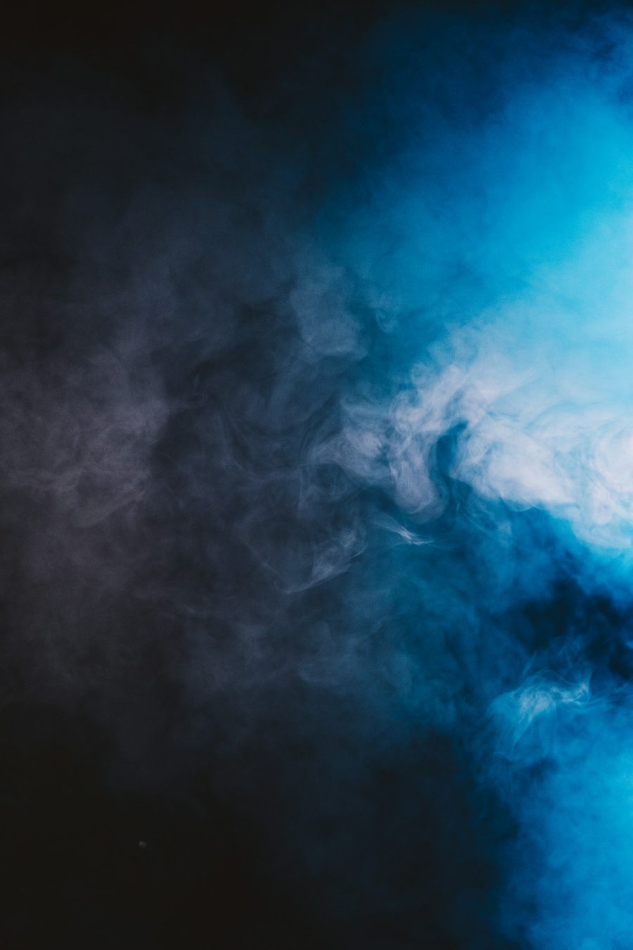 Humo azul iluminado girando sobre fondo negro