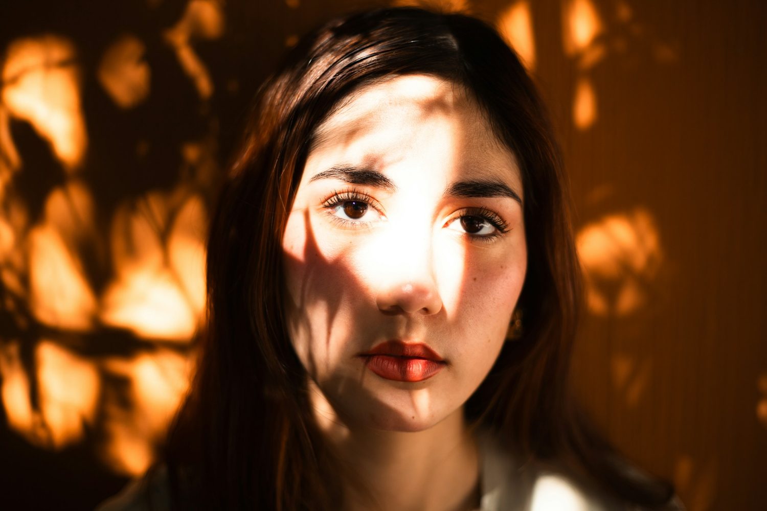 Retrato de una mujer con sombras de hojas proyectadas sobre el rostro